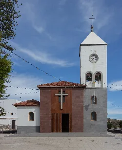 Iglesia con torre y reloj en Fasnia, Tenerife, bajo cielo azul.