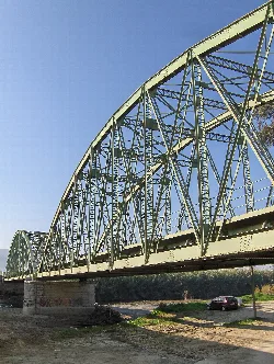 Metal bridge with arch and truss structure over the river.