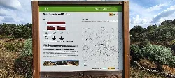 Trail sign in Cedillo with map and details in a natural setting.