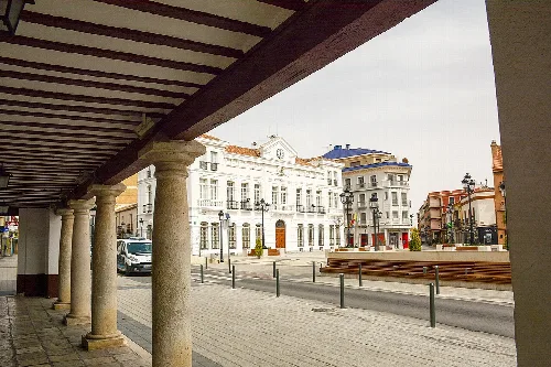 Säulen und Dach im Vordergrund mit Blick auf den Platz und historische Gebäude.