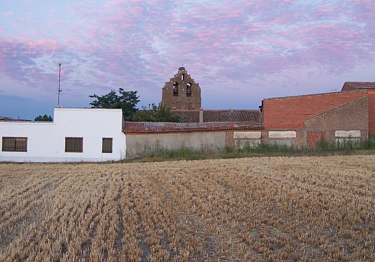 Glockenturm von Pascualgrande mit Häusern und Sonnenuntergangshimmel.
