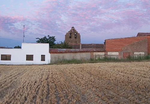 Glockenturm von Pascualgrande mit Häusern und Sonnenuntergangshimmel.