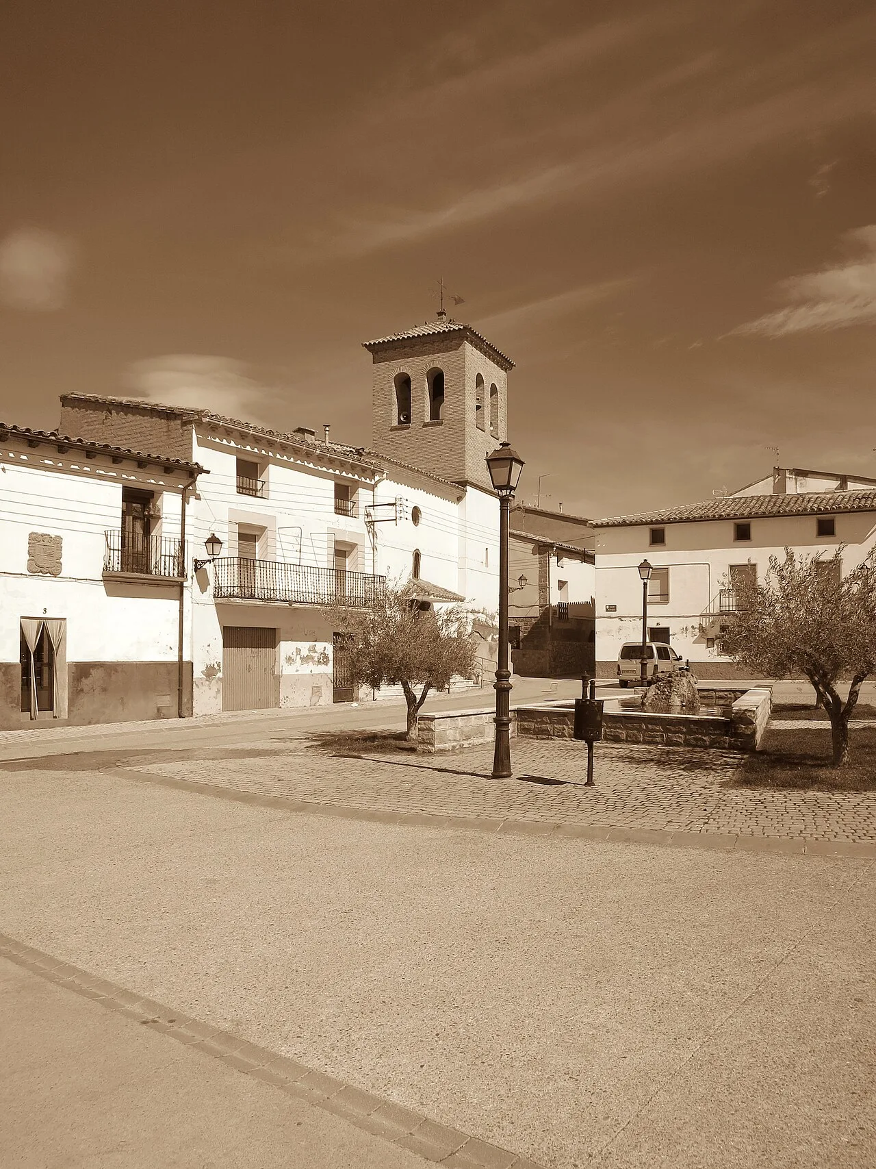 Main square of Tierz with church and trees on a sunny day.