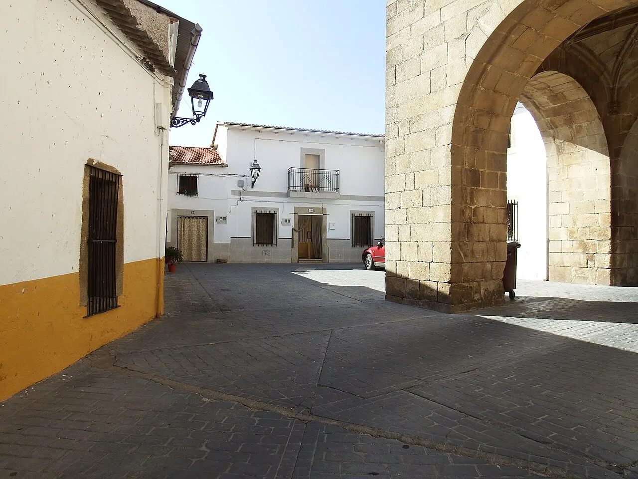 Calle en Arroyomolinos con arco de piedra y casas blancas.