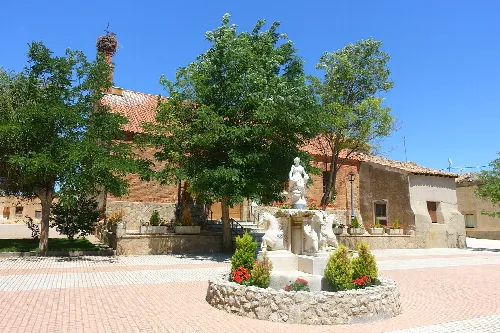 Brunnen und San Pedro Kirche umgeben von Bäumen in Cotanes del Monte.