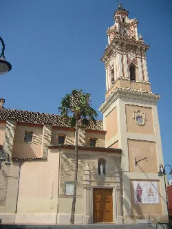 Torre y fachada de la iglesia de San Miguel en Catarroja, con un árbol y cielo azul.