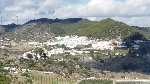Landschaft von Carratraca mit weißen Häusern und Windmühlen auf den Hügeln.