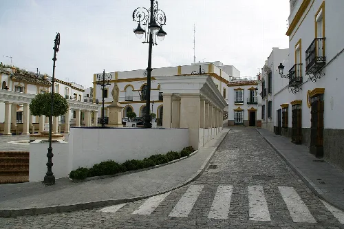 Plaza con edificios blancos y farolas en Las Cabezas de San Juan.