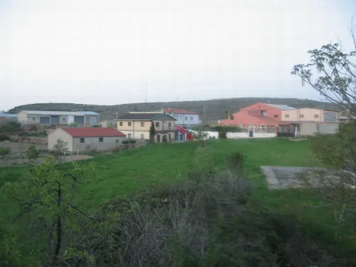 Several houses in a rural landscape with hills and vegetation.