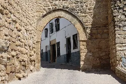 Arco de piedra de la puerta de Granada en Sabiote, con calle empedrada.