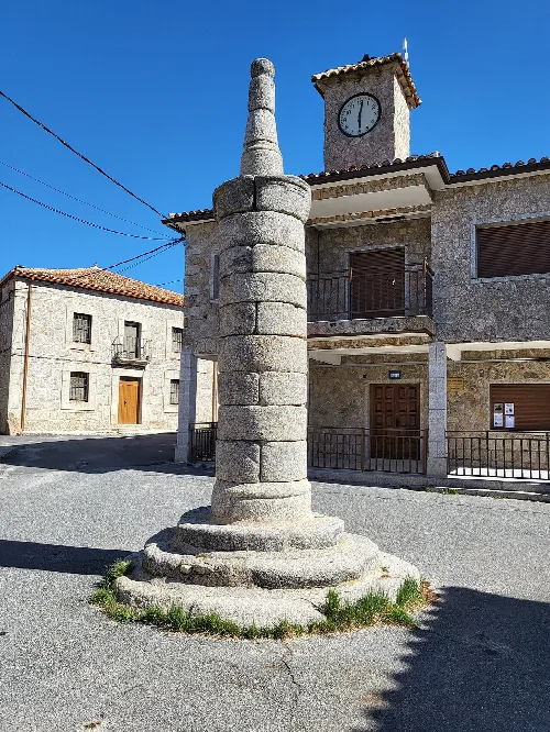 Steinsäule in Cepeda la Mora mit einer Uhr im Hintergrund.