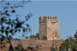 Cabrilla-Turm in Posadas, Córdoba, mit blauem Himmel und Vegetation.