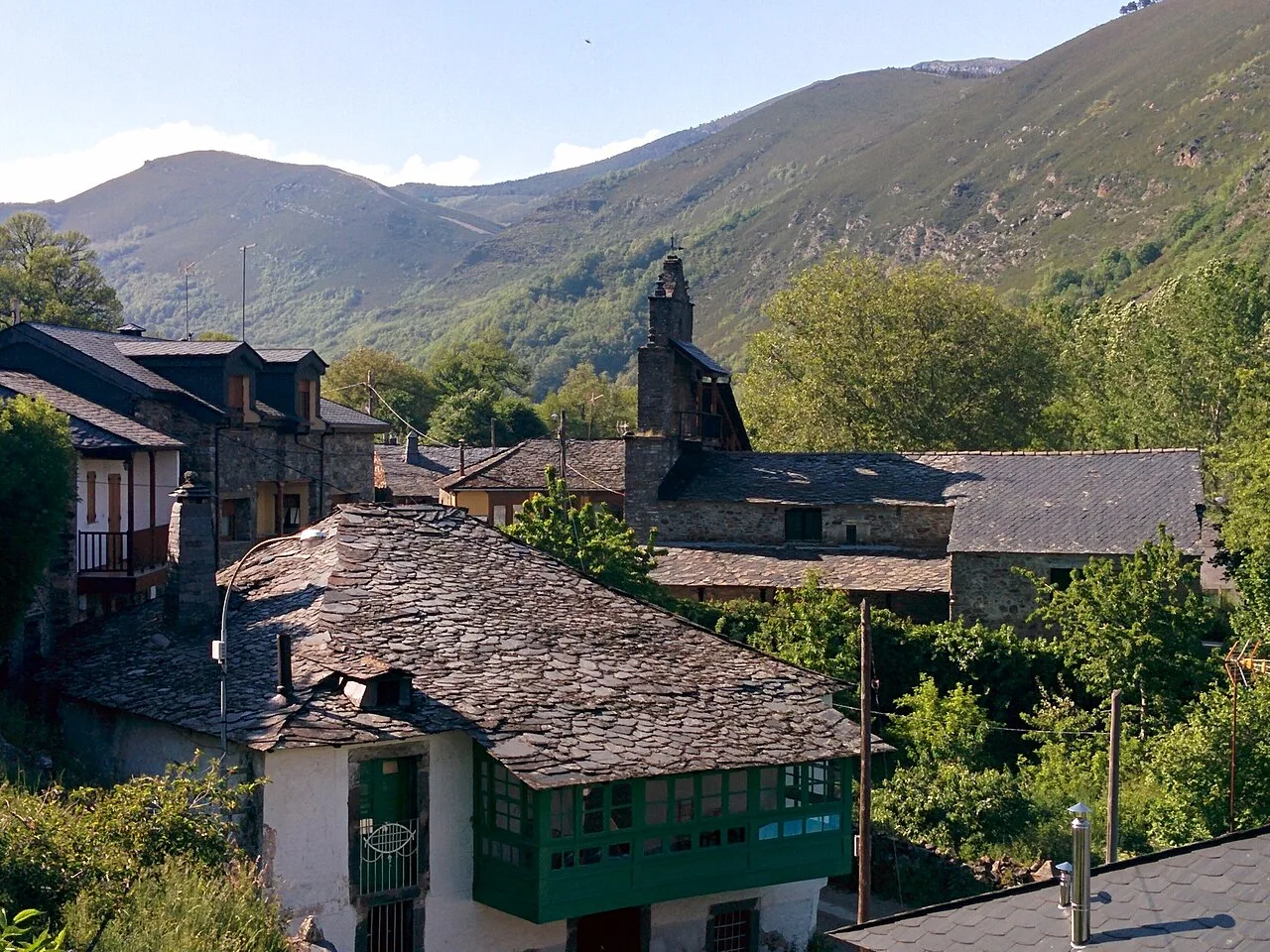 Casas tradicionales en Pereda de Ancares con montañas verdes.