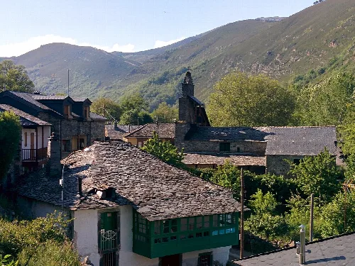 Traditionelle Häuser in Pereda de Ancares mit grünen Bergen.
