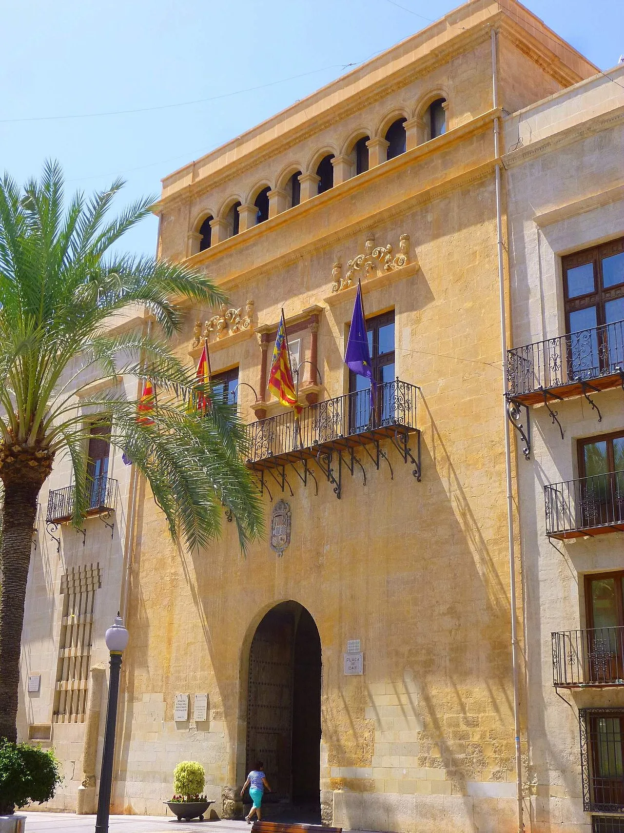 Edificio con arcos en la parte superior y banderas en el balcón principal.