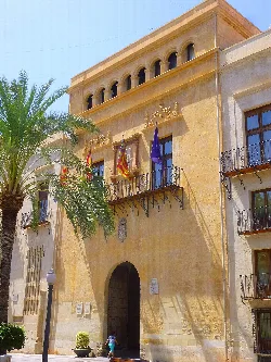 Edificio con arcos en la parte superior y banderas en el balcón principal.