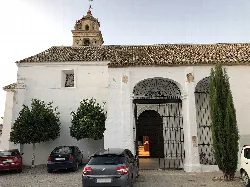 White church facade with arched entrance and trees beside it.