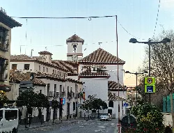 Church with bell tower and red roof in La Zubia.