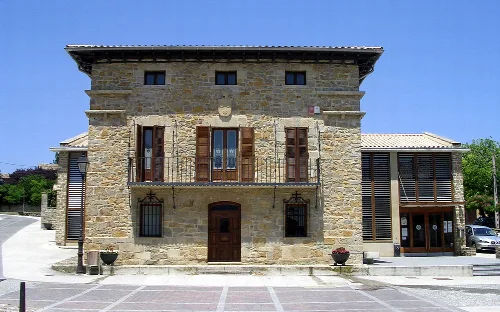 Edificio de piedra con ventanas de madera y balcón en Cendea de Cizur.