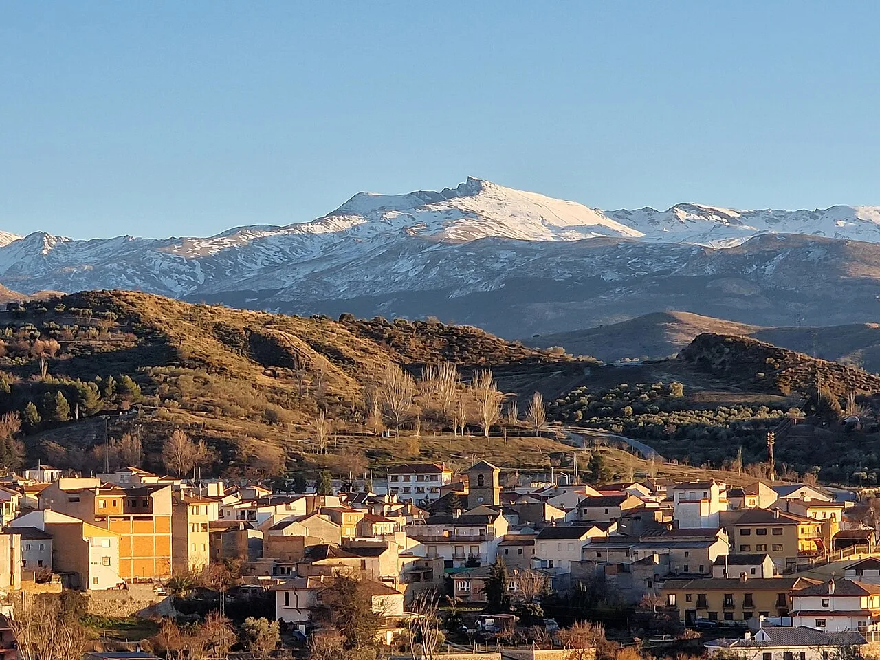 Vista de la localidad de Beas de Granada, en la provincia de Granada (España), con Sierra Nevada al fondo. Imagen tomada desde la carretera GR-3107.