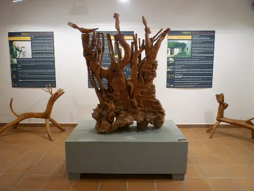 Escultura de madera en un museo, con paneles informativos en la pared.