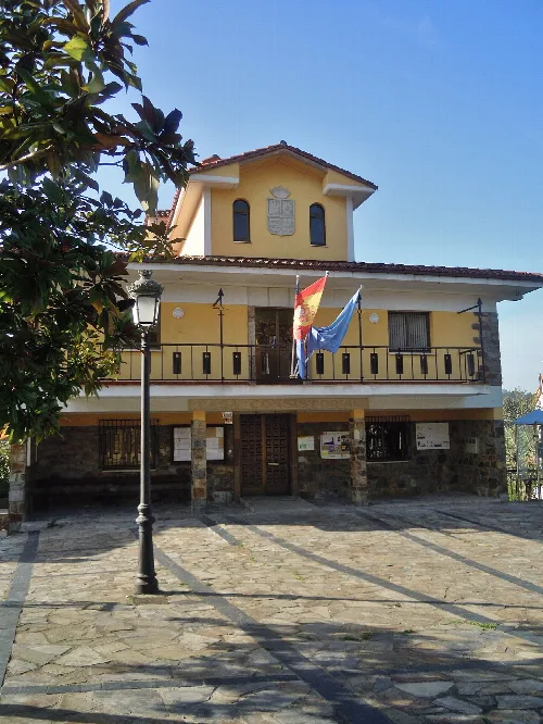 Edificio amarillo con balcón y banderas en la fachada.