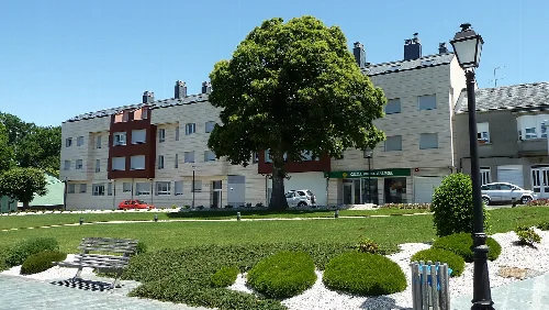 Platz mit großem Baum, Bänken und Wohnhäusern in Pol, Lugo.