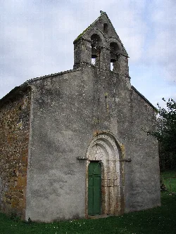 Iglesia románica con campanario de dos arcos y puerta de arco de medio punto.
