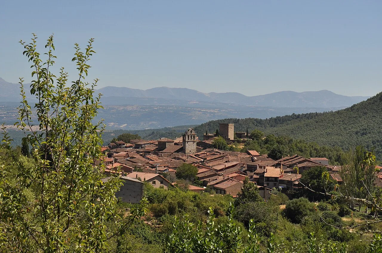 Vista de un pueblo con tejados de teja y montañas al fondo.