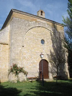 Stone chapel facade with wooden door and small round window.