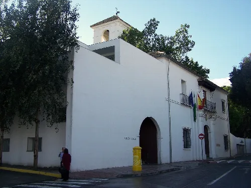 Edificio blanco con arcos y banderas en la fachada, en Tomares.