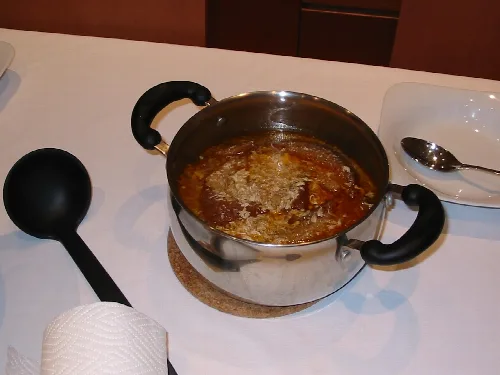 Garlic soup in a stainless steel pot on a white table