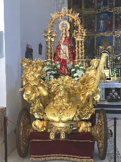 Virgin of Charity on a golden float with white flowers.