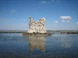 Torre de Tamarit en las salinas de Santa Pola, rodeada de agua y cielo azul.
