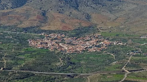 Luftaufnahme eines Dorfes umgeben von grünen Feldern und Bergen in Granada
