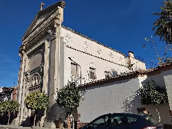 White church facade with classical details and trees on the sidewalk.