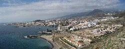 Panoramablick auf Los Cristianos mit Strand, Gebäuden und Bergen.