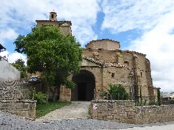 Church in Añorbe with tree and stone wall.