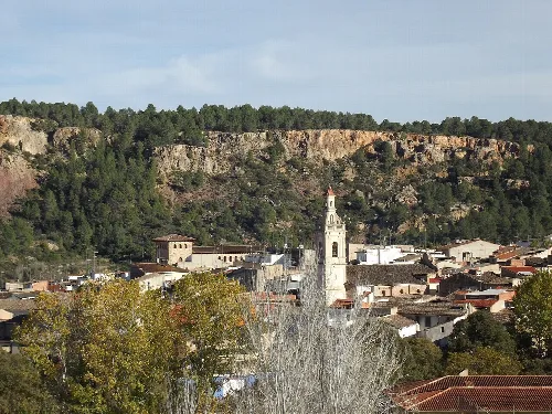 Blick auf eine Stadt mit Kirche und grünen Hügeln.