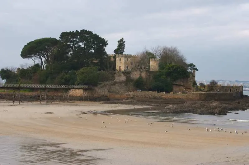 Schloss Santa Cruz in Oleiros, Galicien, in der Nähe des Strandes und von Bäumen umgeben.
