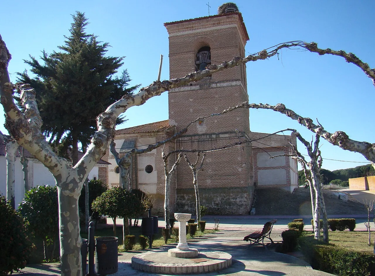 Fountain and church in Moraleja de las Panaderas, Valladolid, with trees and benches.