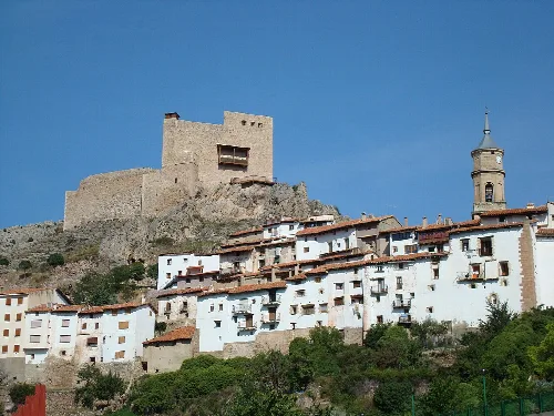 Weiße Häuser am Hang und eine Burg auf dem Hügel.