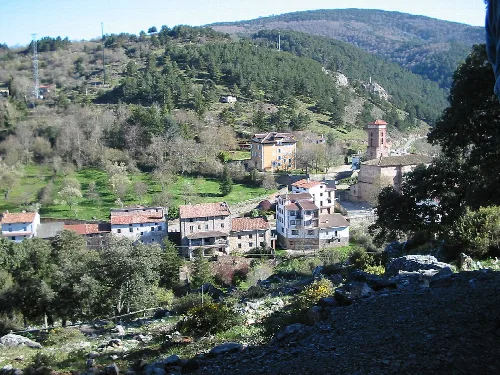 Vista de casas y una iglesia en un valle rodeado de colinas verdes en Ortigosa de Cameros.
