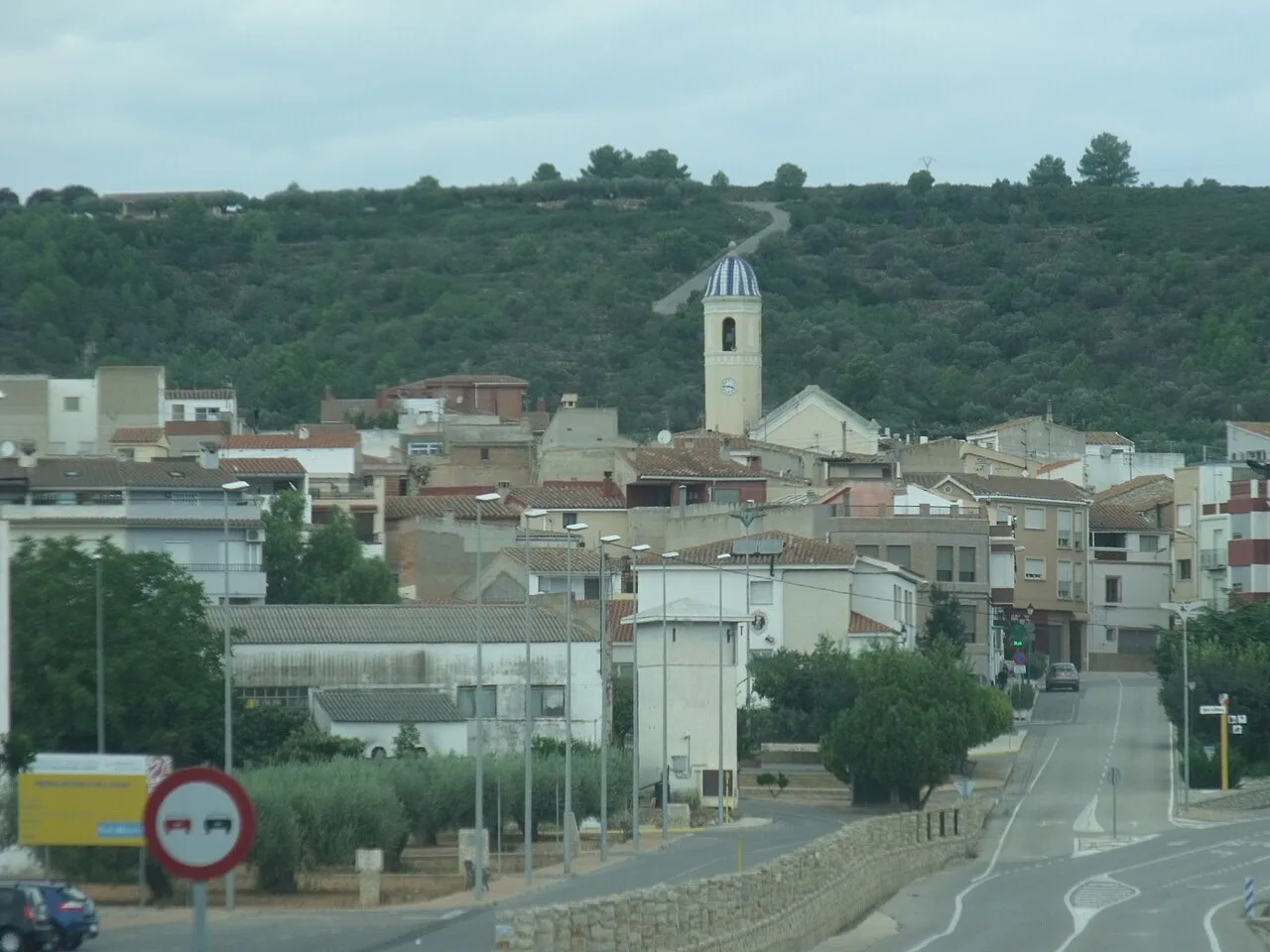 Städtische Landschaft von Vall d'Alba mit Kirche und Häusern an einem bewölkten Tag.