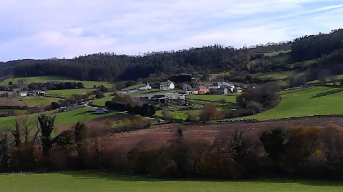 Ländliche Landschaft mit Häusern und grünen Hügeln in Barreiros, Lugo.