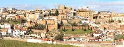 Panorámica de Cáceres con edificios históricos y murallas en un día soleado.