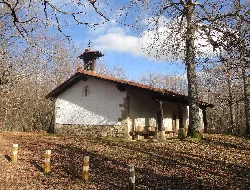 Pequeña ermita blanca con tejado de tejas rojas y campanario en Etxarri Aranatz.