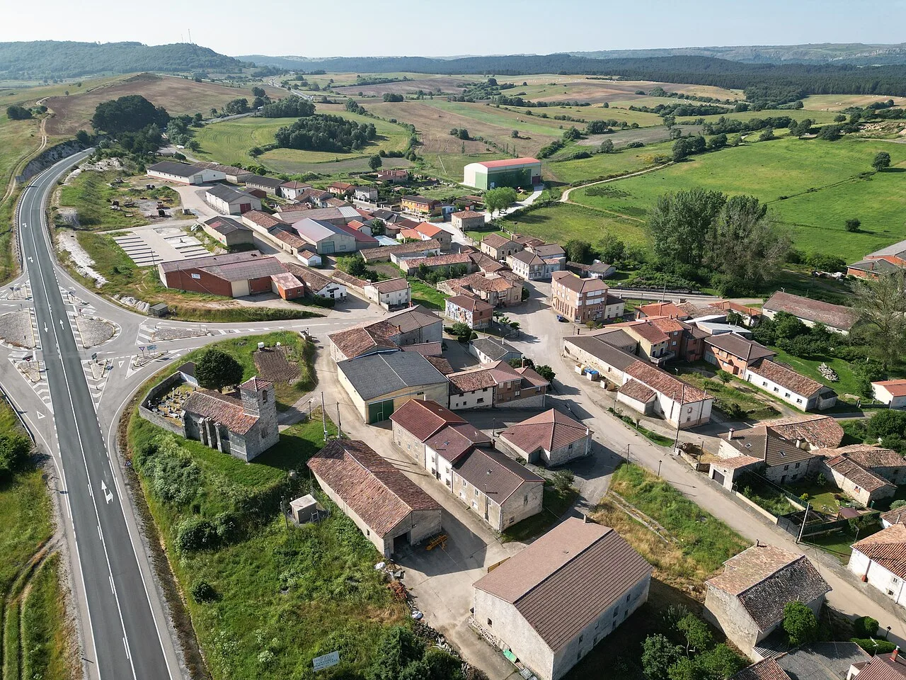 Aerial view of a village with houses and a road in a rural environment.