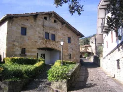 Calle empedrada con casas de piedra y balcones en Garay, Vizcaya.