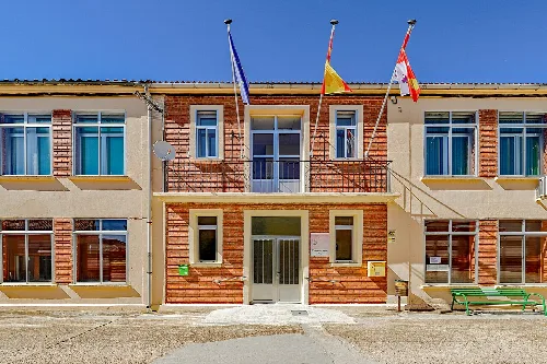 Town hall building of Pinilla Trasmonte with flags on the facade.